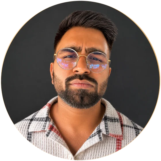 Portrait of Neeraj Singh Shekhawat, GTM engineer, wearing round gold-rimmed glasses and a checked shirt